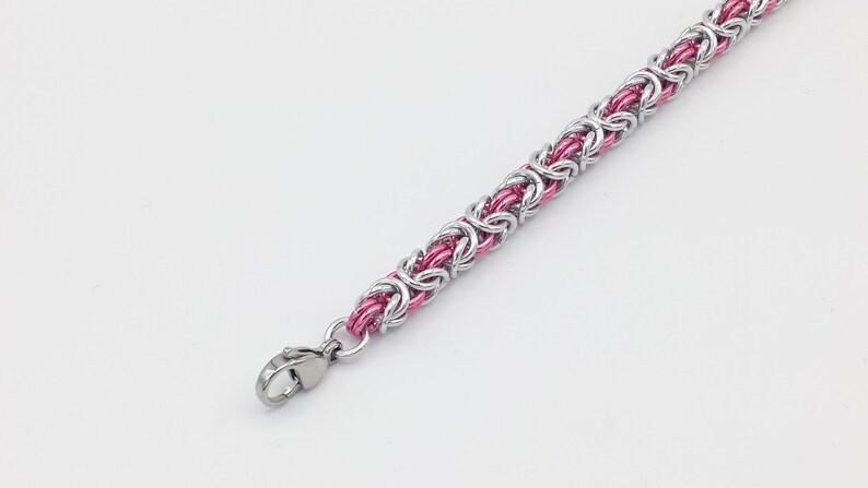 May include: A silver and pink chain bracelet with a lobster clasp closure.