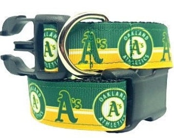 Puede incluir: Un collar para mascotas de color verde y amarillo con el logotipo de los Oakland Athletics y el emblema del equipo A's. El collar incluye una hebilla de plástico negra de liberación lateral y una anilla en D de metal plateado.