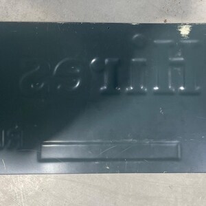 K&ouml;nnte beinhalten: Ein rechteckiges, dunkelgr&uuml;nes Metallschild mit gepr&auml;gter wei&szlig;er Schrift. Das Schild tr&auml;gt die Worte "HAVE A LITTLE FUN" und andere Texte. Ein kleiner wei&szlig;er Aufkleber mit der Nummer "119-1" befindet sich in der oberen linken Ecke. Das Schild hat ein abgenutztes Aussehen.