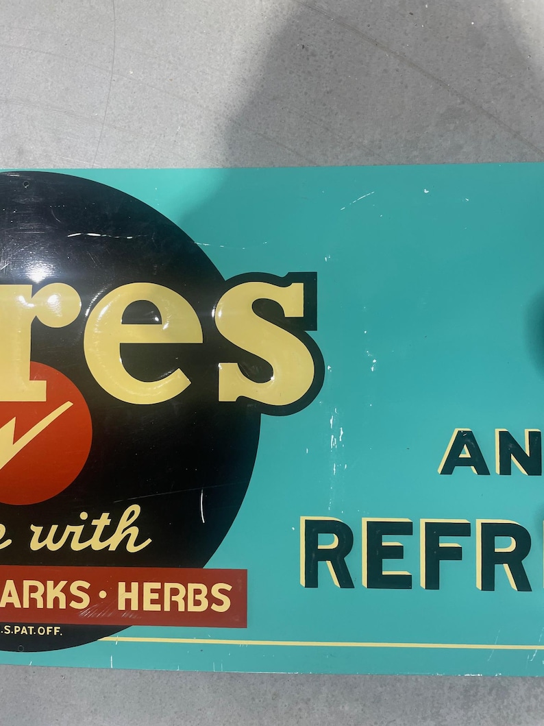 K&ouml;nnte beinhalten: Vintage Metallschild mit dem Wort "res" in gelben Buchstaben, einem roten Kreis mit einem wei&szlig;en H&auml;kchen und den Worten "with SPARKS HERBS" auf einem braunen Rechteck. Der Hintergrund ist t&uuml;rkis mit den Worten "AN REFR" in Schwarz.