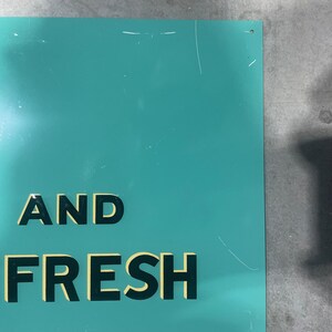 K&ouml;nnte beinhalten: Ein t&uuml;rkisfarbenes Metallschild mit den Worten "AND FRESH" in fetten, schwarzen Blockbuchstaben mit gelber Umrandung. Das Schild hat ein paar Kratzer und den Text "DONASCO 3-49" unten rechts.