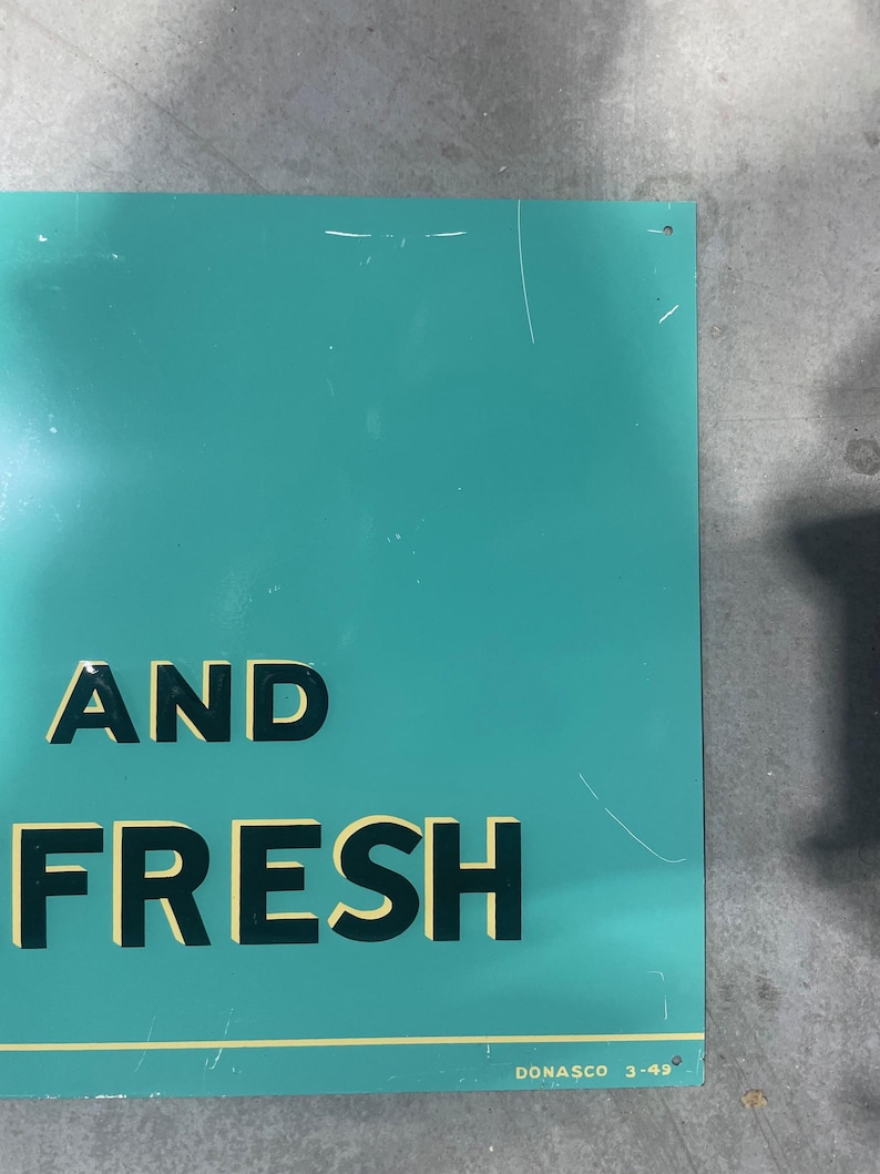 K&ouml;nnte beinhalten: Ein t&uuml;rkisfarbenes Metallschild mit den Worten "AND FRESH" in fetten, schwarzen Blockbuchstaben mit gelber Umrandung. Das Schild hat ein paar Kratzer und den Text "DONASCO 3-49" unten rechts.