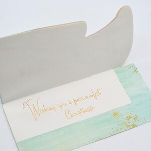 May include: A light green card with a gold glitter design and the text "Wishing you a purr-r-fect Christmas".