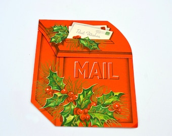 May include: A vintage orange mailbox-shaped Christmas card with the word "MAIL" in white. The card features holly and berries, and a letter that says "Best Wishes".