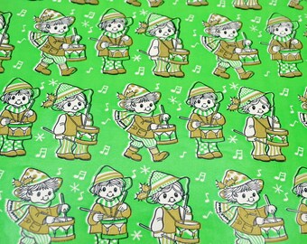 Könnte beinhalten: Ein hellgrünes Geschenkpapier mit einem sich wiederholenden Muster aus Zeichentrickfiguren, die Hüte und Schals tragen und Trommeln spielen. Das Design enthält kleine weiße Musiknoten und sternförmige Symbole zwischen den Figuren.