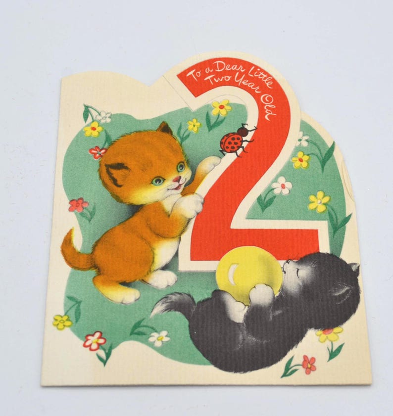 Puede incluir: Tarjeta de cumplea&ntilde;os vintage con dos gatitos de dibujos animados. Un gatito naranja est&aacute; de pie y el otro gatito negro est&aacute; acostado. La tarjeta tiene un n&uacute;mero 2 rojo y el texto "To a Dear Little Two Year Old."