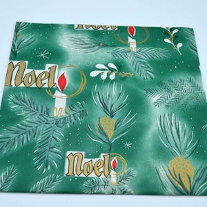 May include: Green wrapping paper with a repeating pattern of white candles with red flames, gold Noel text, and pine branches. The paper has a vintage Christmas theme.
