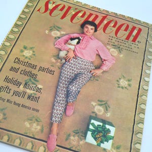 May include: A December 1954 issue of Seventeen magazine featuring a person in a pink ruffled blouse and patterned pants holding a small dog. The cover includes the text Christmas parties and clothes, Holiday hairdos, gifts you'll want.