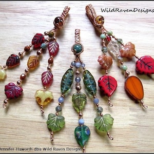 May include: Two handmade copper wire wrapped leaf charms with glass leaf beads in shades of green, red, orange, and yellow.  WildRavenDesigns.