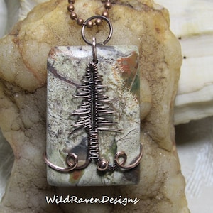 May include: A rectangular pendant with a camouflage pattern and a copper wire tree design. The pendant is suspended from a copper chain. The words "WildRavenDesigns" are at the bottom of the pendant.