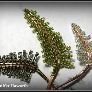 May include: Three wire-wrapped fern sprigs, one in silver, one in gold, and one in green. The ferns are arranged in a fan shape.