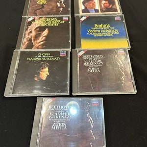 Peut inclure: Une collection de six disques compacts de musique classique de Beethoven, Brahms et Chopin. Les disques sont tous dans des boîtiers de type jewel avec des épines noires et présentent des images des compositeurs sur la face avant. Le texte sur les disques comprend les noms des compositeurs, les titres des œuvres et les noms des interprètes, notamment Vladimir Ashkenazy et Zubin Mehta.
