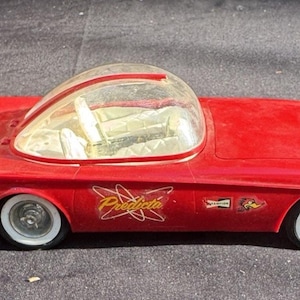 Puede incluir: Coche de juguete rojo con un techo de plástico transparente y la palabra "Predicta" impresa en el lateral. El coche tiene un diseño futurista y es un juguete vintage.