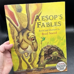 Może przedstawiać: Biały ceramiczny kubek z czarnym uchwytem i napisem "But First, Coffee" czarną, pogrubioną czcionką. Kubek stoi na białej powierzchni. Kubek ma 10 cm wysokości.