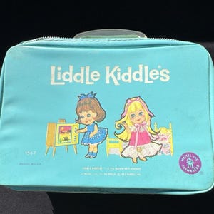 May include: A vintage turquoise Liddle Kiddles carrying case. The case features the text "Liddle Kiddles" in white, along with illustrations of two dolls and a television. The Mattel Inc. Toymakers logo is on the lower right corner.