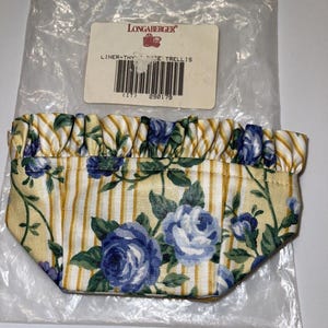 May include: A yellow and white striped fabric liner with a blue rose pattern. The liner has a ruffled edge and is labeled "Longaberger Liner-Thyme Rose Trellis (11) 290179".
