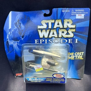 May include: A blue and white Star Wars Episode I die-cast metal Micro Machines toy of a Trade Federation Droid Starfighter with opening wings. The toy is packaged in a blue and white cardboard box with a picture of a character from the film.