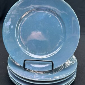 May include: A stack of six blue ceramic dinner plates. The plates have a glossy finish and a slightly raised rim.