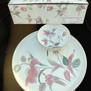 May include: A cream-colored serving set with a floral design, including a large plate and a small bowl. The set is decorated with pink flowers and green leaves. The box reads "SILK FLOWERS by MIKASA".