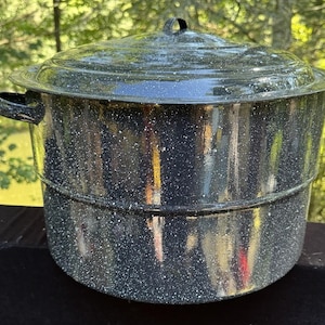 May include: A speckled black and white enamelware preserving pot with a lid and side handles. The pot is cylindrical with a wide base and a slightly flared rim. The lid has a small handle.