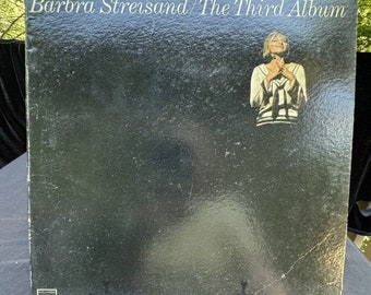 May include: A black vinyl record album with a white label and a photo of Barbra Streisand on the cover. The album title is "Barbra Streisand/The Third Album".