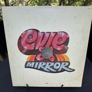 May include: A vintage vinyl record album cover featuring a red, white, and blue graphic of the word "Evie" with a black circle in the center and the word "Mirror" in blue letters below.