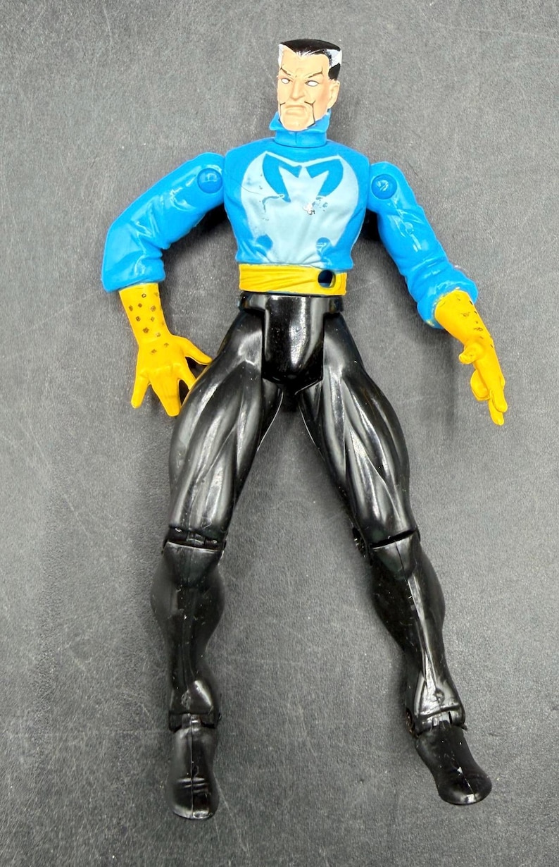 May include: Action figure of a character in a blue and white top with a yellow belt and gloves, and black pants. The figure has a stern expression and is posed with arms outstretched. The figure is a collectible toy.