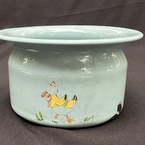 May include: A light blue ceramic chamber pot with a yellow and blue painted bird design.