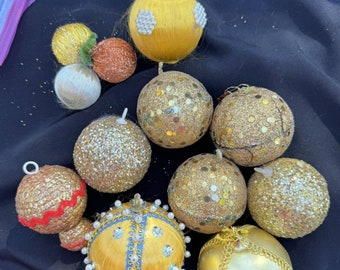 May include: A collection of vintage Christmas ornaments in gold, silver, and yellow. Some ornaments are covered in sequins, while others are made of fabric. The ornaments are perfect for adding a touch of vintage charm to your holiday decor.
