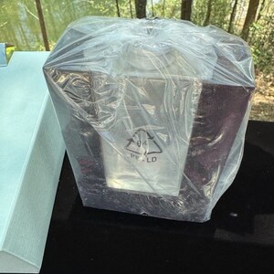 Puede incluir: Un marco de madera negro con un inserto de vidrio transparente, envuelto en una bolsa de plástico transparente. El marco tiene un símbolo de reciclaje con el texto "PE-LD" impreso en él.