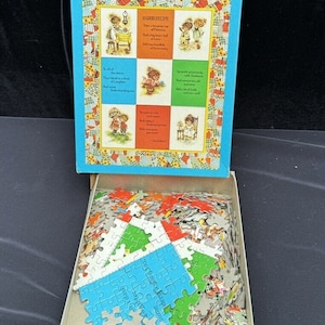 Può includere: Una scatola di puzzle vintage Sta-Tru patchwork con un coperchio blu e una base marrone. Il coperchio presenta un design patchwork colorato con una citazione su una buona ricetta. La scatola è aperta e i pezzi del puzzle sono sparsi all'interno. La scatola misura 40,6 x 50,8 cm e contiene oltre 500 pezzi.