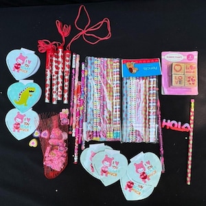Puede incluir: Una colección de artículos de artesanía con temática del Día de San Valentín que incluye lápices, sellos de goma y recortes de papel. Los lápices son coloridos y tienen varios diseños. Los sellos de goma presentan corazones, la palabra "amor" y la frase "sé mío". Los recortes de papel son rosas y blancos y presentan corazones y la frase "You Bear-y Much".