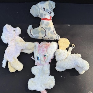Può includere: Quattro giocattoli di peluche vintage: un maiale rosa, un gatto bianco con orecchie rosa, un cane bianco con un orecchio giallo e un dalmata grigio e bianco.