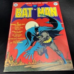 Puede incluir: Una portada de cómic vintage con Batman en un traje azul y amarillo, volando sobre una ciudad. La portada es roja y amarilla con el título "BATMAN" en letras grandes y en negrita. El texto de la portada dice "6 Spine-Tingling Stories, 3 Super-Size Pin-Ups, How-To-Draw Batman, 3D Diorama Cut-Out, Batmaze & Puzzles, Batman of the Movies".