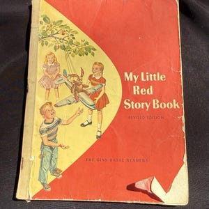 Könnte beinhalten: Vintage "My Little Red Story Book" mit rotem und gelbem Einband. Das Cover zeigt Illustrationen von Kindern und einem Hasen mit einem Flugzeug. Es ist eine überarbeitete Ausgabe aus der Reihe "The Ginn Basic Readers".