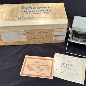 Puede incluir: Visor de tiras de película Viewlex Previewer Jr. de 35 mm vintage con caja y documentación originales. La caja es de color beige con texto azul y un logotipo de Viewlex. El visor es gris con una lente y un soporte metálico. Garantía de por vida.