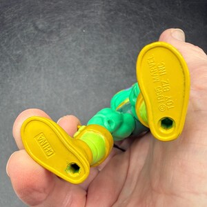 Op de afbeelding: Een vintage actiefiguur, voornamelijk groen en geel. De gele voeten van de figuur dragen de tekst "CHINA" en "&copy;1995 MARVEL TOY BIZ INC.". Het figuur wordt in een hand gehouden.