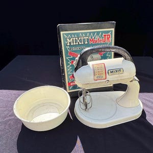 Könnte beinhalten: Vintage Mixit Master Jr. batteriebetriebener Mixer mit weißem und schwarzem Griff, einer weißen Rührschüssel und der Originalverpackung. Auf der Box stehen die Worte "Mixit Master Jr." und "Battery Operated".