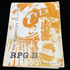 May include: A vintage book titled "Computer Programming RPG II" by Shelly & Cashman. The cover features a yellow and orange abstract design.