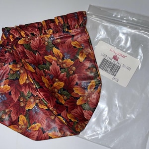 May include: A red, orange and yellow floral fabric liner with a ruffled edge. The liner is packaged in a clear plastic bag with a white label that reads "LINER-1995 SU FALL FOLIAGE 26034".