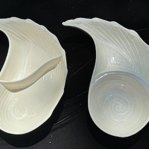 Puede incluir: Dos platos de servir de cerámica blanca con un diseño texturizado único. Un plato tiene una sección dividida, mientras que el otro tiene un solo tazón redondo.