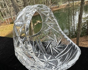 May include: A clear glass bowl with a cut crystal design. The bowl has a handle and is shaped like a basket.