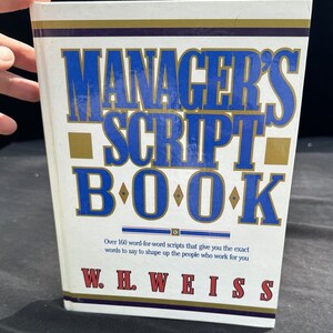 May include: A white book with a blue and gold title that reads "Manager's Script Book" by W.H. Weiss. The book cover states that it contains over 160 word-for-word scripts to help shape up employees.