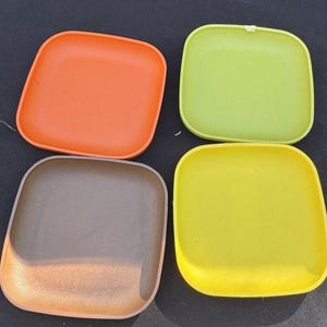 以下が含まれることがあります： オレンジ、グリーン、ブラウン、イエローの竹製の正方形のプレート4枚