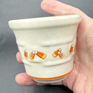 May include: A white ceramic mug with a black handle and the text "But first, coffee" in a black, handwritten-style font. The mug is on a white surface.