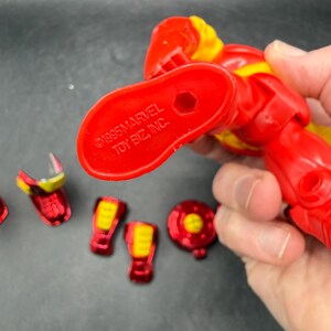 May include: Red and yellow Iron Man action figure with detachable parts. The figure is marked with "&copy;1995 MARVEL TOY BIZ, INC." on the foot. Includes various red and yellow armor pieces.