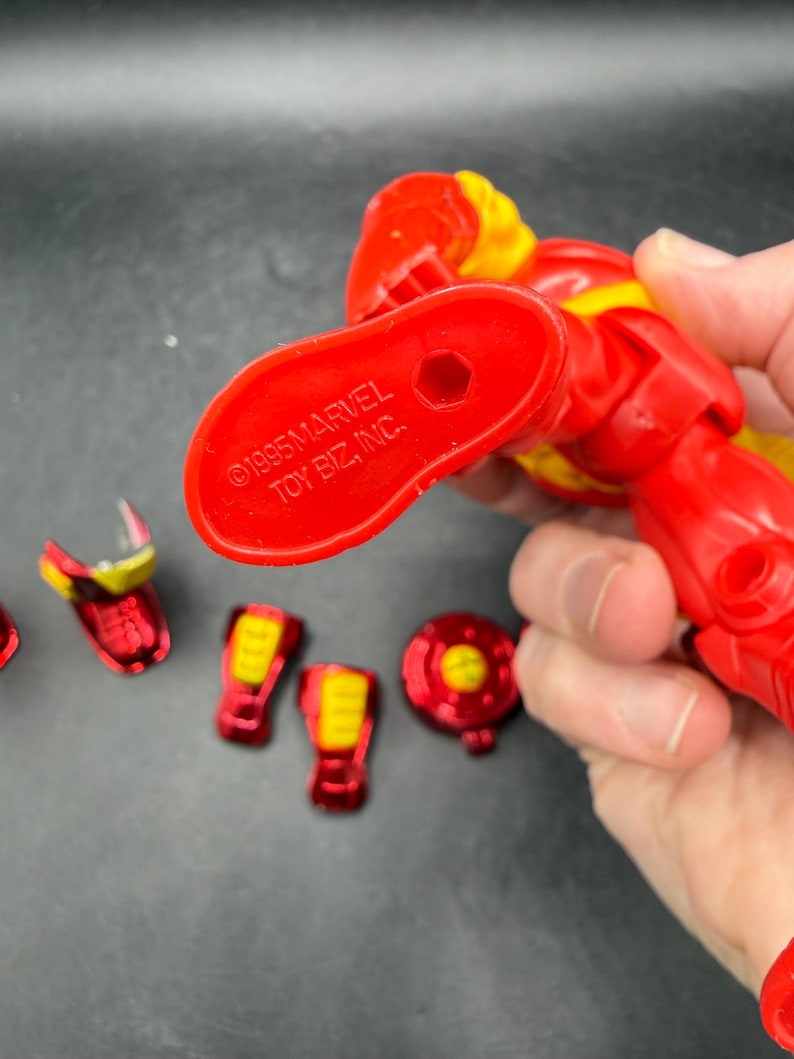 May include: Red and yellow Iron Man action figure with detachable parts. The figure is marked with "&copy;1995 MARVEL TOY BIZ, INC." on the foot. Includes various red and yellow armor pieces.