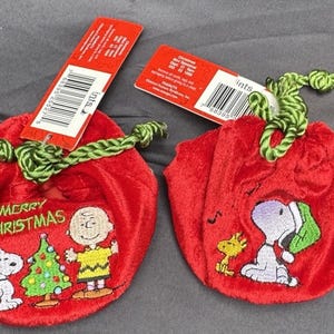 Può includere: Due sacchetti rossi con coulisse e cordini verdi, con personaggi ricamati di Snoopy e Peanuts. Un sacchetto dice "Merry Christmas". Ogni sacchetto ha un'etichetta rossa attaccata.