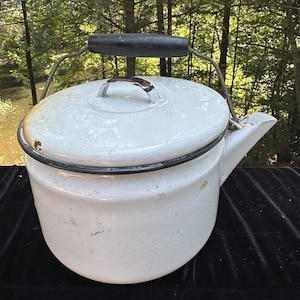 Peut inclure: Théière en émail blanc avec une poignée en bois noir et un bord noir autour du couvercle. La théière a un bec verseur et un couvercle avec une petite poignée.