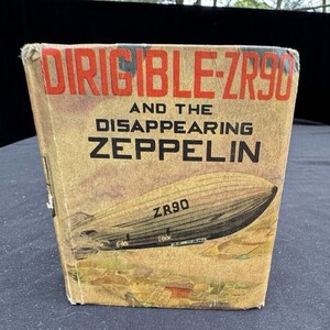 May include: A vintage book cover with the title "DIRIGIBLE ZR90 AND THE DISAPPEARING ZEPPELIN". The cover features a black and white illustration of a dirigible with the text "ZR90" on the side.